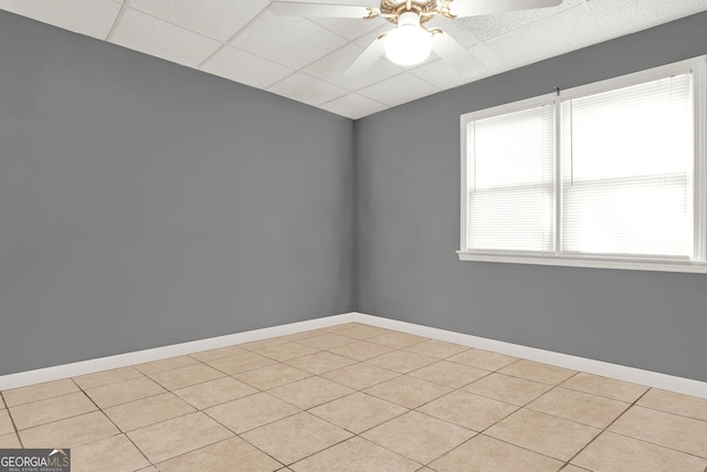 spare room with a paneled ceiling, light tile patterned floors, and ceiling fan