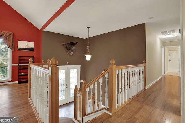 staircase with french doors, vaulted ceiling, and hardwood / wood-style flooring