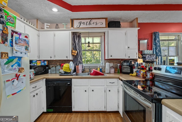 kitchen with white cabinetry, black appliances, sink, and light wood-type flooring