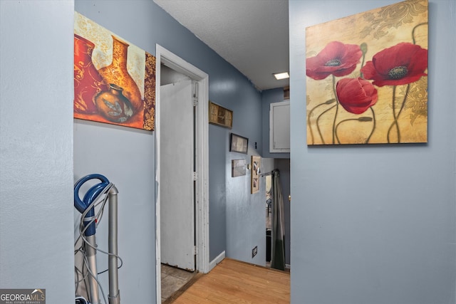 hallway with light hardwood / wood-style flooring and a textured ceiling