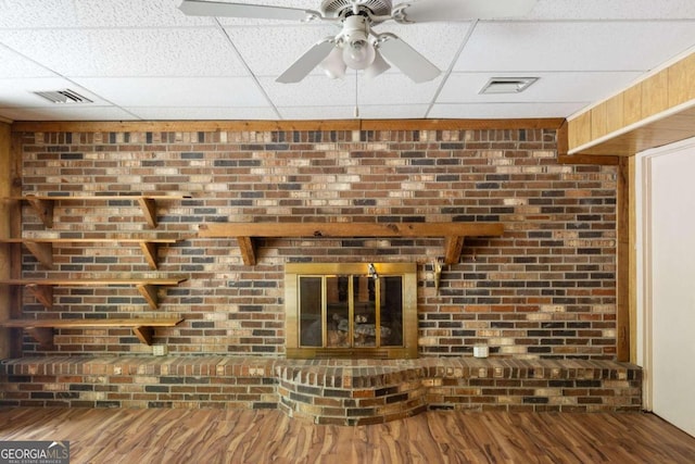 details featuring a brick fireplace, a paneled ceiling, wood-type flooring, and ceiling fan