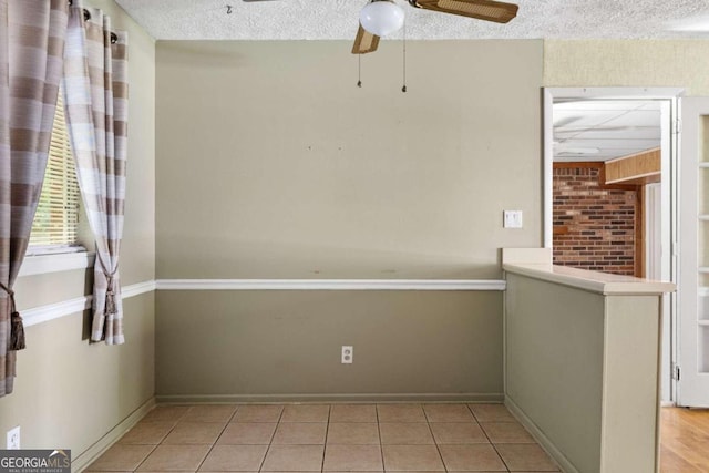 tiled spare room with a textured ceiling and ceiling fan