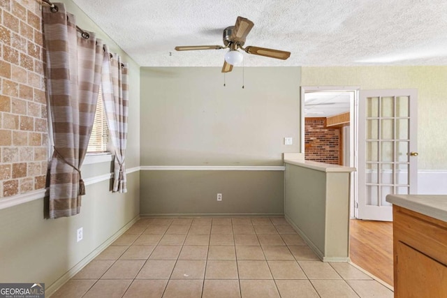 empty room with ceiling fan, a textured ceiling, and light tile patterned floors