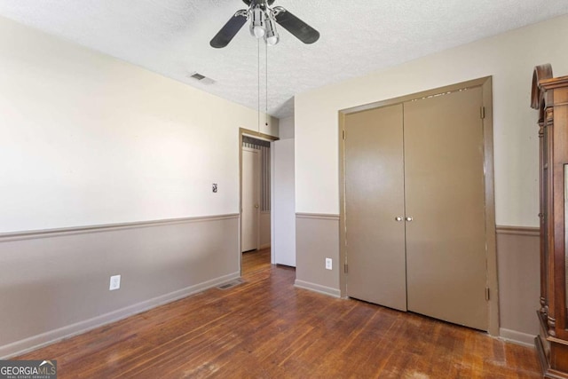 unfurnished bedroom featuring dark wood-type flooring, ceiling fan, and a textured ceiling