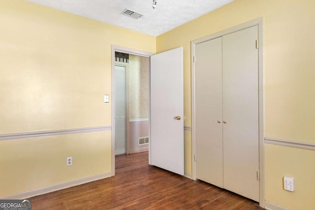 unfurnished bedroom with a textured ceiling and dark hardwood / wood-style flooring