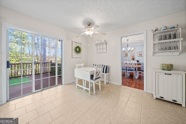 tiled dining room with a textured ceiling and ceiling fan with notable chandelier