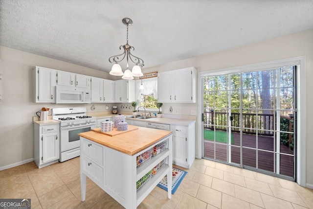 kitchen featuring white appliances, sink, hanging light fixtures, white cabinets, and a notable chandelier