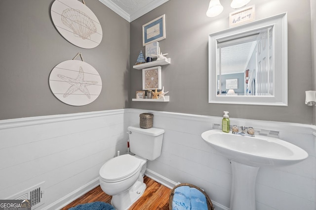 bathroom with ornamental molding, hardwood / wood-style floors, and toilet