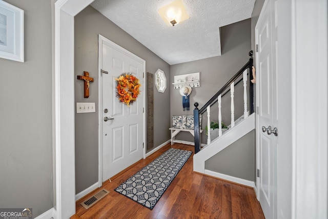 entryway with a textured ceiling and dark hardwood / wood-style floors