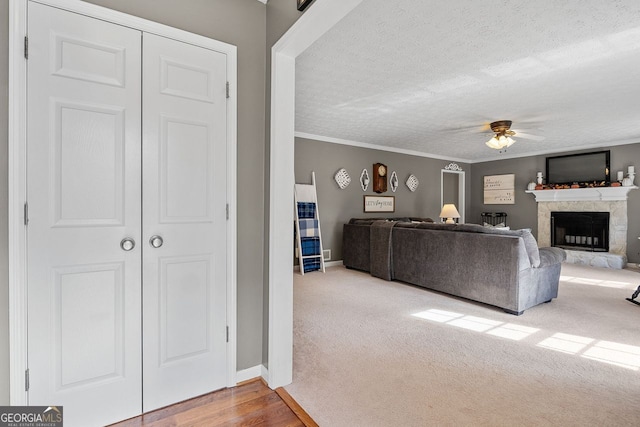 living room with ornamental molding, a textured ceiling, wood-type flooring, and ceiling fan