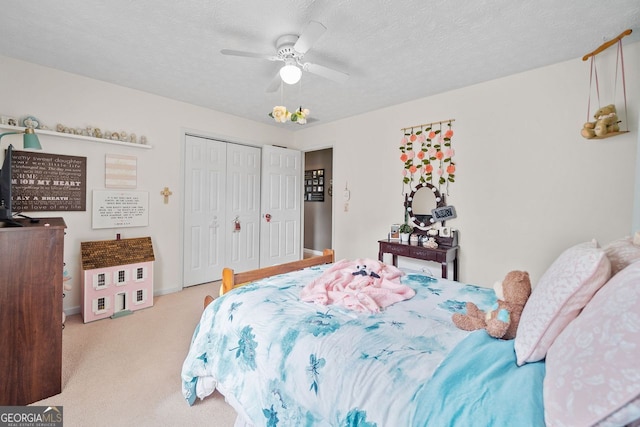 bedroom with a closet, ceiling fan, light carpet, and a textured ceiling