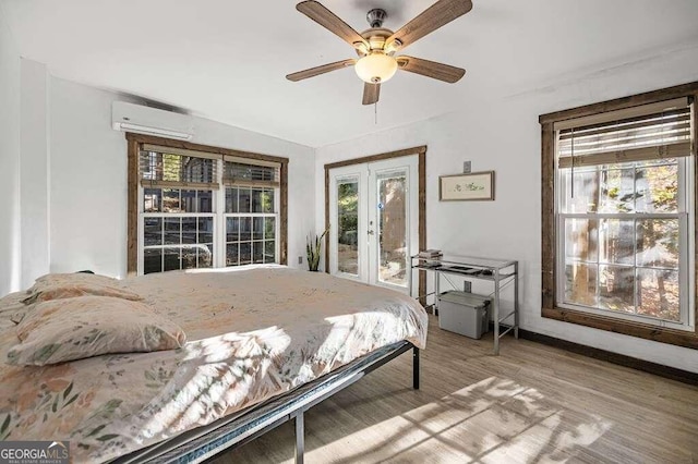 bedroom with access to outside, light hardwood / wood-style flooring, an AC wall unit, and ceiling fan