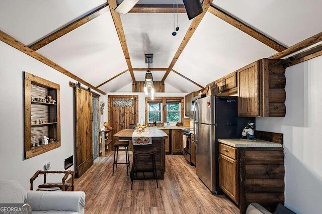 kitchen featuring a breakfast bar area, wood-type flooring, a center island, lofted ceiling with beams, and stainless steel appliances