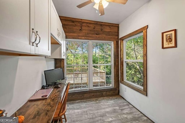 office featuring wooden walls, hardwood / wood-style flooring, and ceiling fan