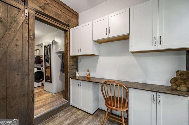 kitchen featuring white cabinetry, stacked washer / drying machine, a barn door, and hardwood / wood-style floors