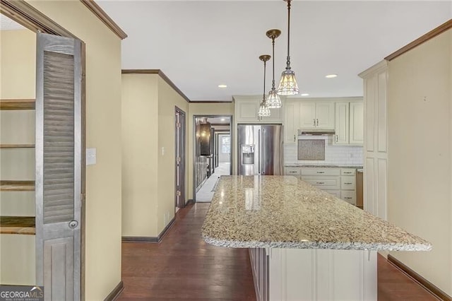 kitchen featuring stainless steel fridge, decorative backsplash, hanging light fixtures, light stone countertops, and a center island