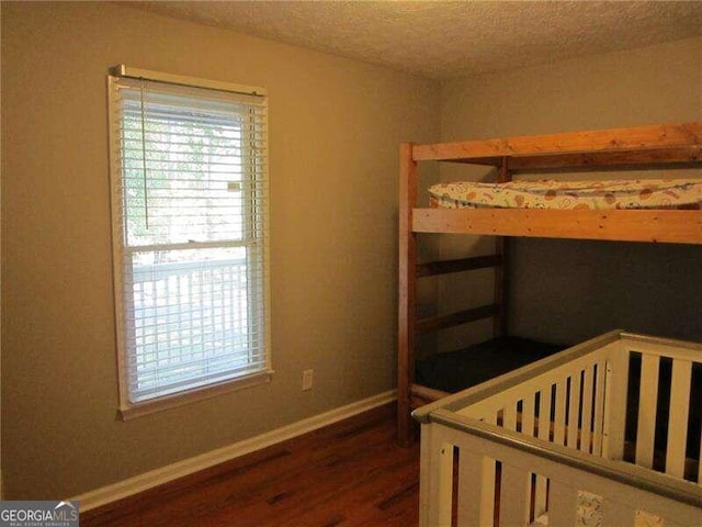 bedroom with a textured ceiling and dark hardwood / wood-style floors