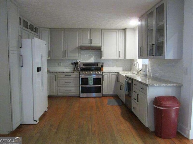 kitchen featuring decorative backsplash, appliances with stainless steel finishes, a textured ceiling, and dark hardwood / wood-style floors