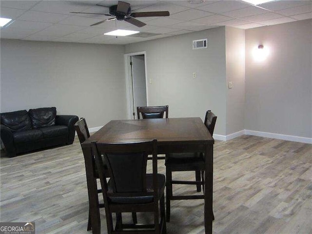 dining area with light hardwood / wood-style floors, a paneled ceiling, and ceiling fan