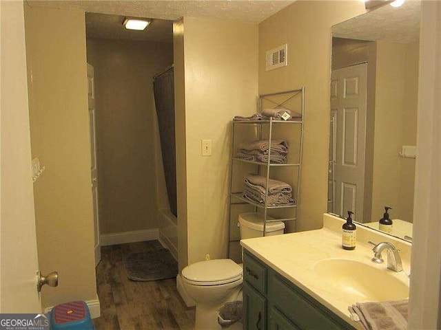 full bathroom featuring a textured ceiling, hardwood / wood-style flooring, shower / bathtub combination with curtain, toilet, and vanity