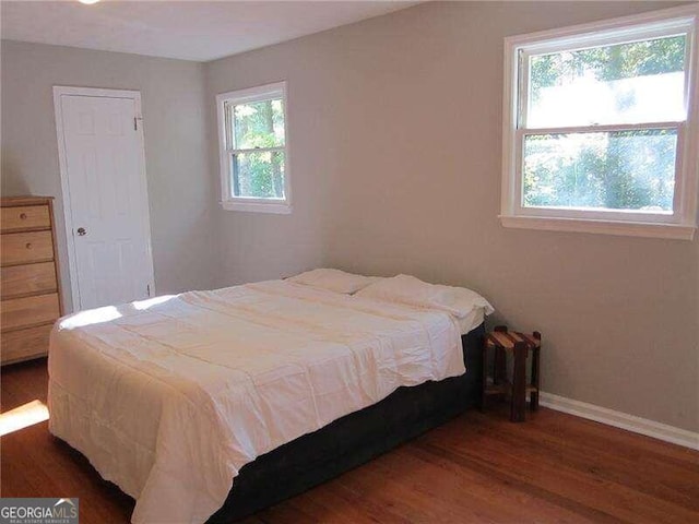 bedroom with dark wood-type flooring and multiple windows