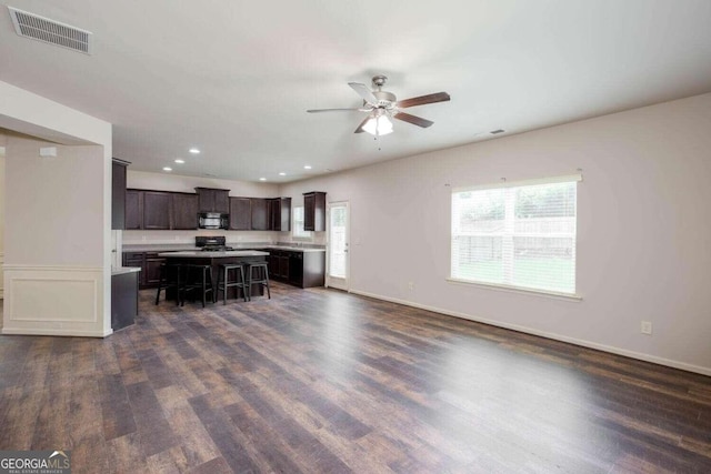 kitchen with a breakfast bar area, black appliances, a center island, and a healthy amount of sunlight