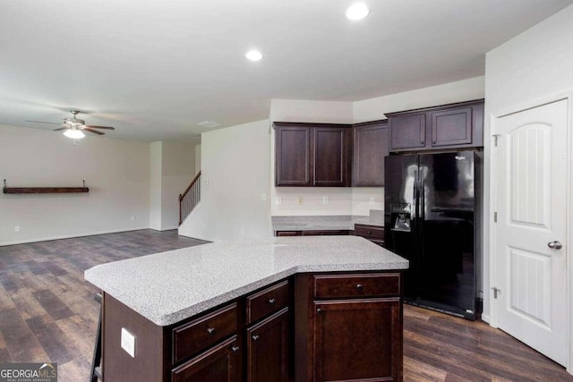 kitchen with dark brown cabinets, a kitchen island, ceiling fan, black fridge, and dark wood-type flooring