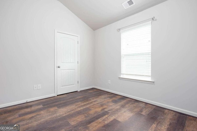 spare room with lofted ceiling, a healthy amount of sunlight, and dark hardwood / wood-style flooring