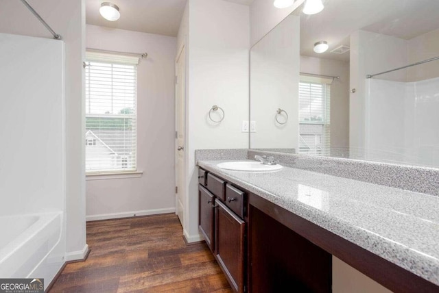 bathroom with vanity, a healthy amount of sunlight, shower / tub combination, and hardwood / wood-style floors