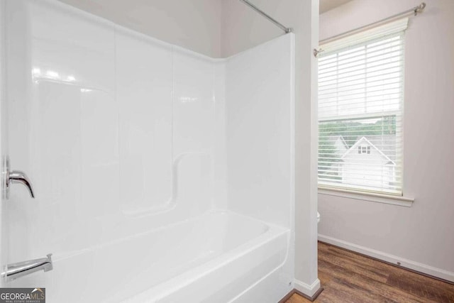 bathroom featuring bathtub / shower combination, hardwood / wood-style floors, and toilet