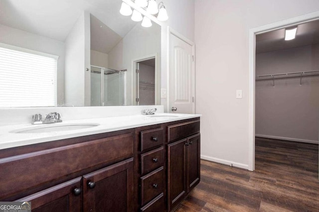 bathroom with vanity, hardwood / wood-style flooring, vaulted ceiling, and a shower with door