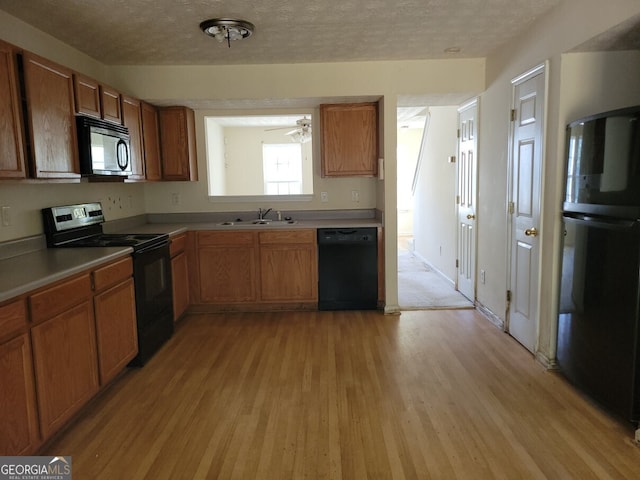 kitchen featuring black appliances, sink, a textured ceiling, light hardwood / wood-style floors, and ceiling fan