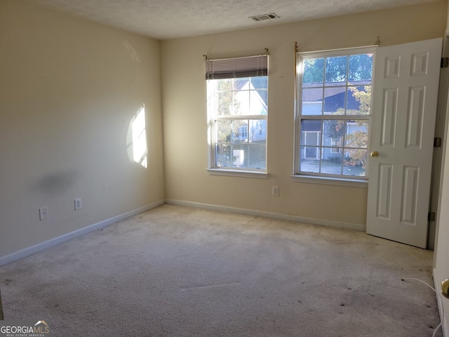 spare room with a textured ceiling and light colored carpet