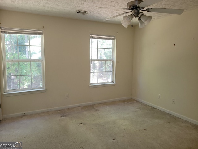 empty room with a textured ceiling, light colored carpet, and ceiling fan