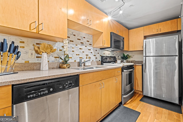 kitchen featuring stainless steel appliances, sink, light hardwood / wood-style floors, and decorative backsplash