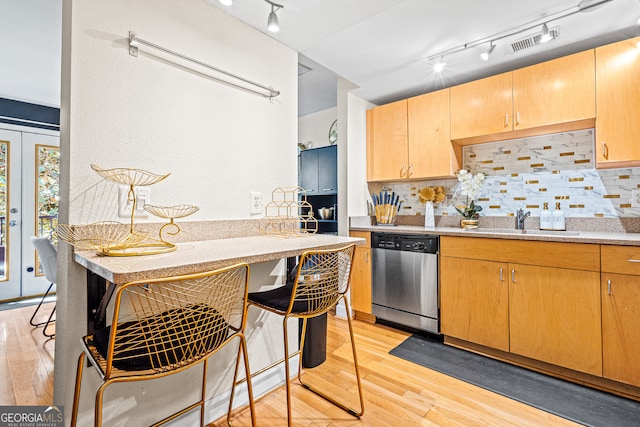 kitchen featuring sink, decorative backsplash, stainless steel dishwasher, and light hardwood / wood-style floors