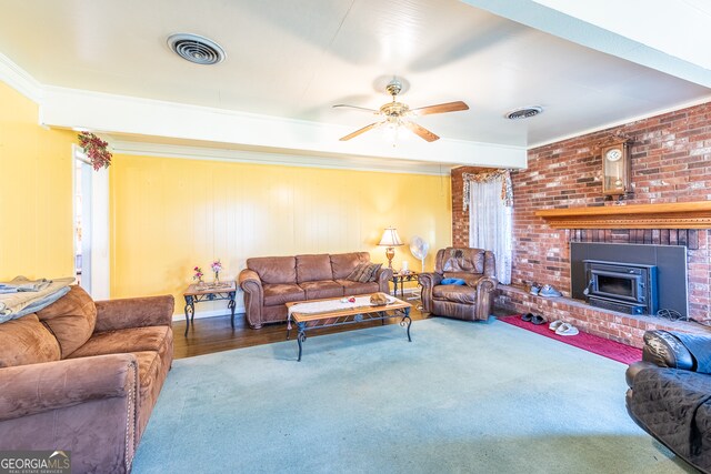 living room featuring ceiling fan, hardwood / wood-style flooring, a wood stove, and crown molding