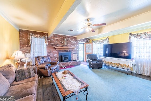 living room with beam ceiling, ceiling fan, wood-type flooring, crown molding, and a wood stove