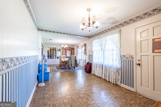 corridor featuring ornamental molding, dark parquet floors, an inviting chandelier, and wood walls