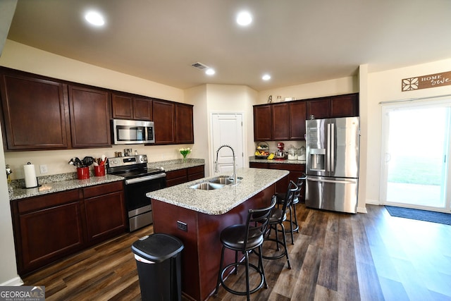 kitchen featuring sink, a kitchen breakfast bar, dark hardwood / wood-style flooring, an island with sink, and appliances with stainless steel finishes