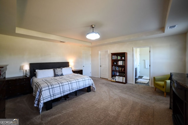 carpeted bedroom with a raised ceiling and connected bathroom