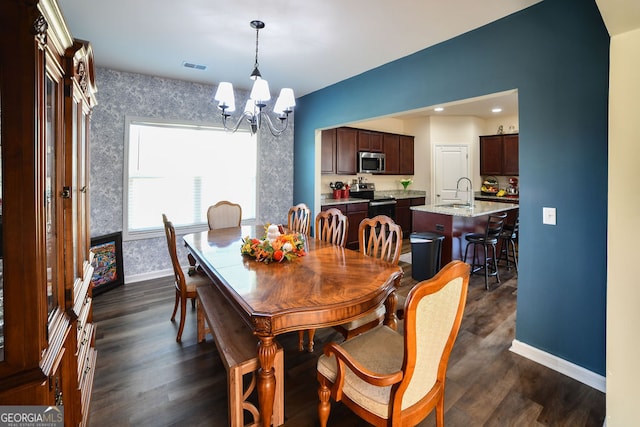 dining space with dark hardwood / wood-style flooring, an inviting chandelier, and sink