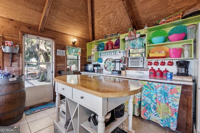 kitchen with wood walls, cooling unit, light tile patterned floors, beamed ceiling, and butcher block counters