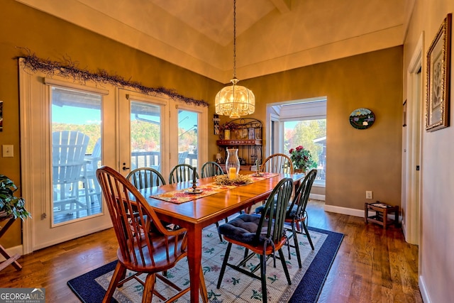 dining space with an inviting chandelier, dark wood-type flooring, vaulted ceiling, and a wealth of natural light