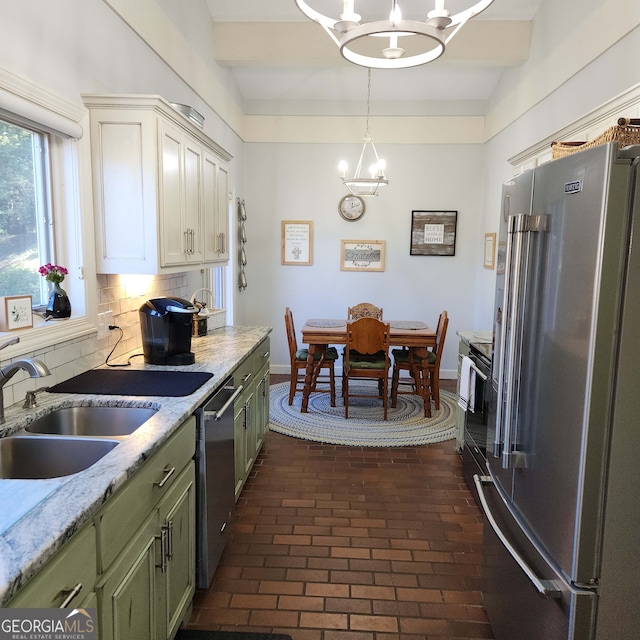 kitchen featuring green cabinets, sink, an inviting chandelier, appliances with stainless steel finishes, and tasteful backsplash