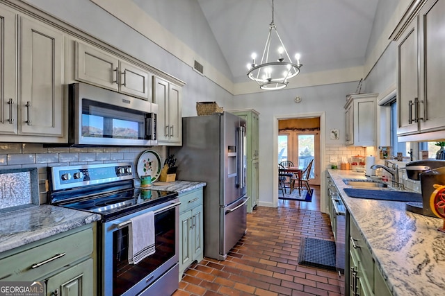 kitchen with appliances with stainless steel finishes, sink, lofted ceiling, decorative light fixtures, and decorative backsplash