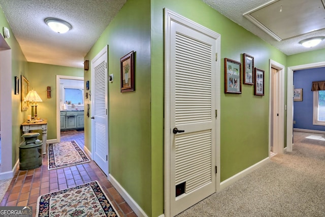 hallway featuring dark carpet and a textured ceiling