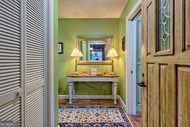 corridor with a textured ceiling and tile patterned flooring