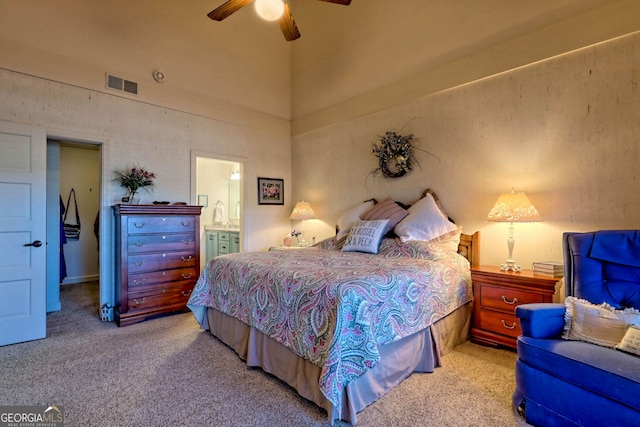 bedroom with light carpet, ensuite bath, and ceiling fan