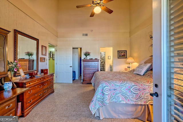 bedroom with ceiling fan, ensuite bathroom, and light colored carpet